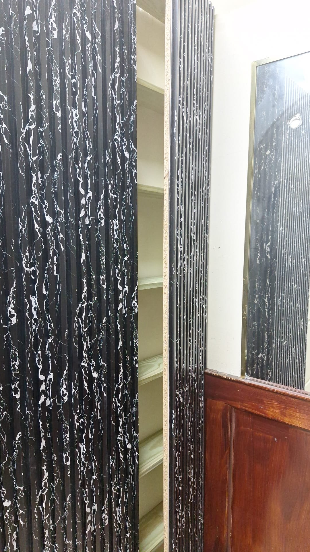 Concealed shelves visible behind an open patterned wall panel