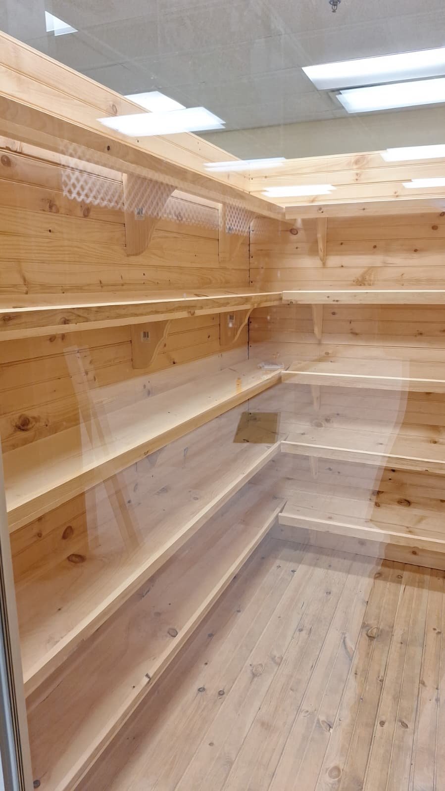 Timber-lined enclosure with corner shelves photographed through glass